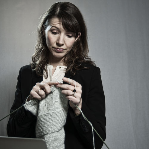 Foto einer sehr genervt strickenden Businessfrau vorm Computer